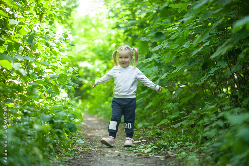 Portrait of smiling girl runs on the trail in the deciduous forest. Waving hands. Forest on bright light background. Portrait of smiling girl runs on the trail in the deciduous forest. Waving hands. Forest on bright light background.