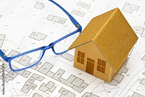 Imaginary cadastral map of territory with buildings and land parcel - concept with a small cardboard house