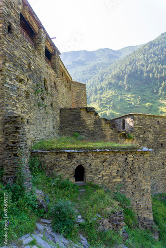 Stone walls and towers of the medieval village of Shatili. Forest and mountains in the background photo