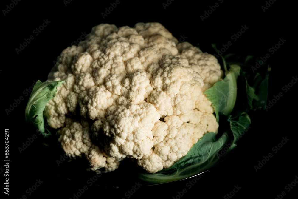 Raw cauliflower in a plate on a black background.Vegetables concept Raw cauliflower in a plate on a black background.Vegetables concept