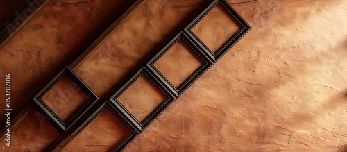 A rustic office with a sienna brown wall, featuring three small empty black frames in a diagonal line. photo