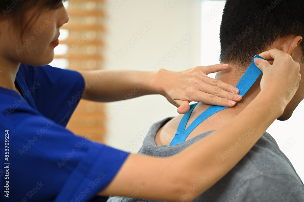 Female physiotherapist applying kinesiology tape on neck of injured male athlete. Sport physical therapy Female physiotherapist applying kinesiology tape on neck of injured male athlete. Sport physical therapy