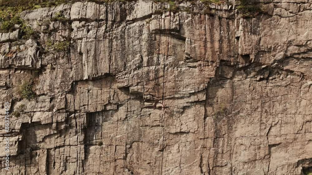 Woman climbing rock wall in Norway, aerial view Woman climbing rock wall in Norway, aerial view