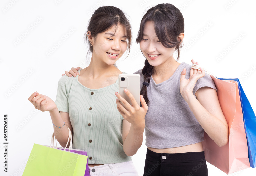Happy Young girls holding with shopping bags and looking at phone Happy Young girls holding with shopping bags and looking at phone