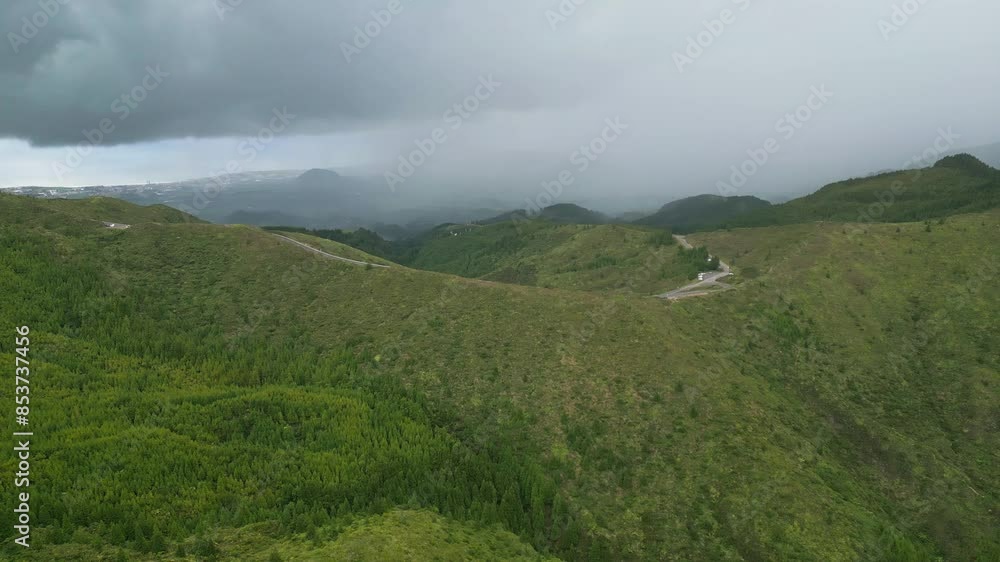 Lush green hills under a cloudy sky with a distant road winding through the landscape Lush green hills under a cloudy sky with a distant road winding through the landscape