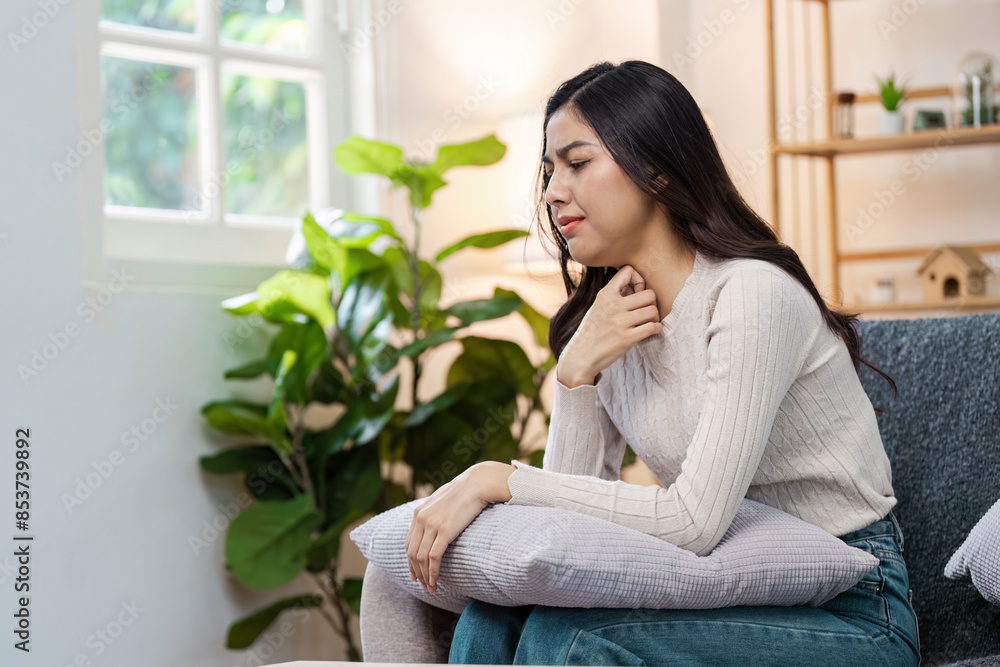 young woman on the couch feel unwell from a sore throat and virus infection. Feeling sick at home with flu young woman on the couch feel unwell from a sore throat and virus infection. Feeling sick at home with flu