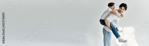 Fotografie A father gives his son a piggyback ride, both laughing.