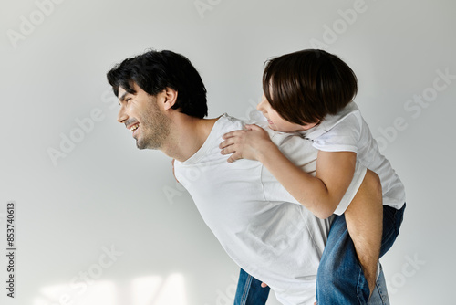 Принти на полотні A father gives his son a piggyback ride, both laughing and enjoying a moment of pure fun