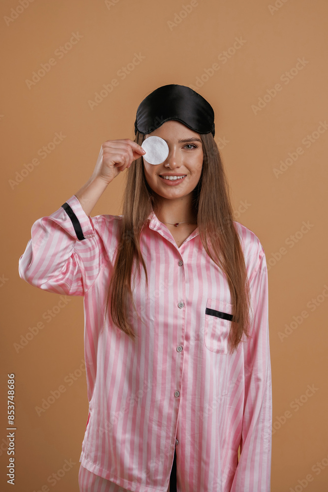 Skin care morning routine, in pink pajama. Young pretty woman is against background in the studio Skin care morning routine, in pink pajama. Young pretty woman is against background in the studio