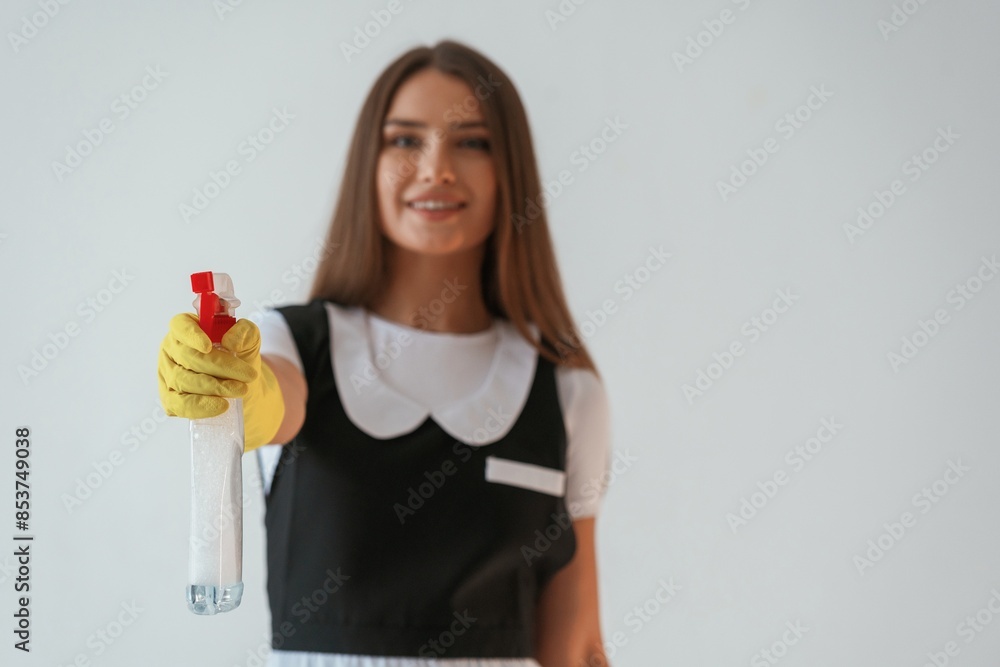 Chambermaid is with cleaning product and tool. Young pretty woman is against background in the studio Chambermaid is with cleaning product and tool. Young pretty woman is against background in the studio