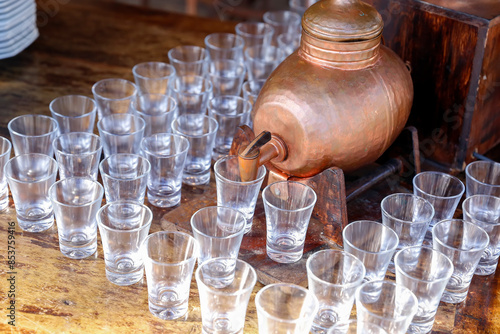 bottle with pinga and several small glass glasses photo