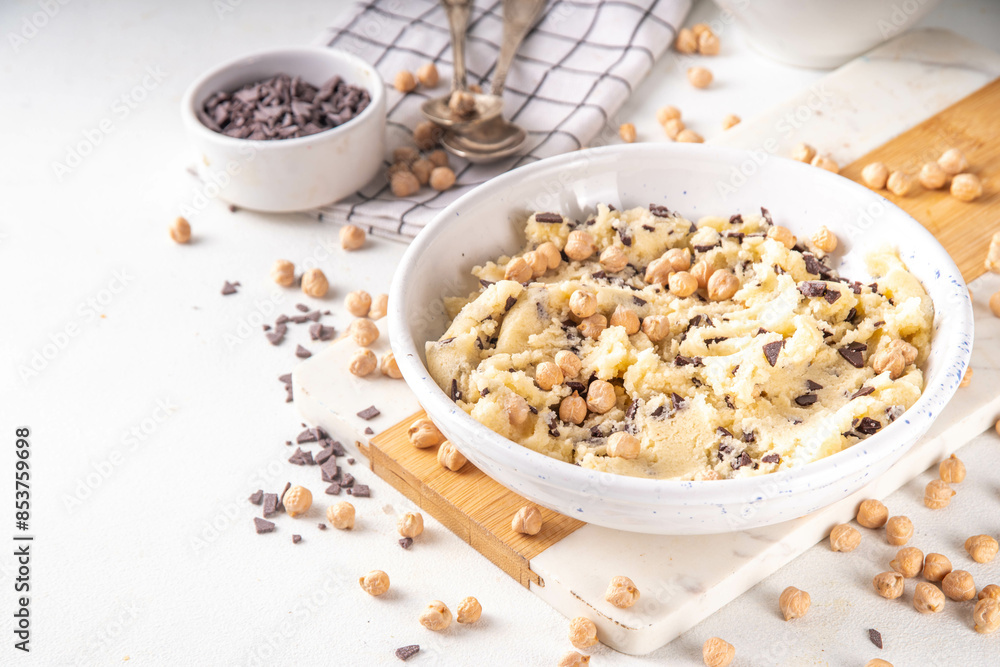 Bowl with vegan Chickpea raw Cookie dough, sweet alternative vegetarian dessert made from Chickpea and chocolate chips. on kitchen table with ingredients Bowl with vegan Chickpea raw Cookie dough, sweet alternative vegetarian dessert made from Chickpea and chocolate chips. on kitchen table with ingredients