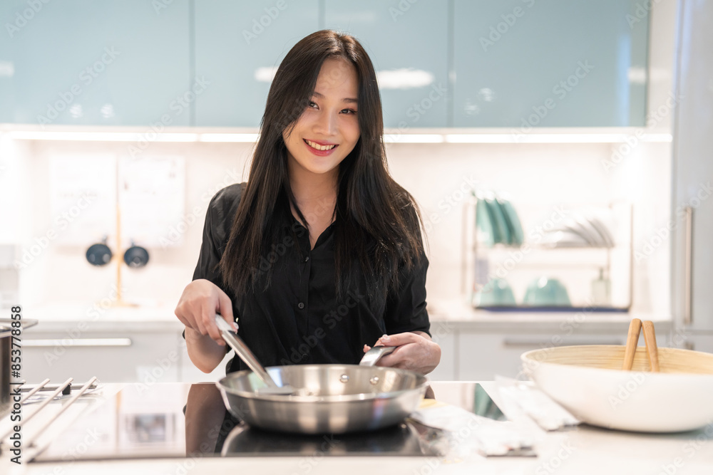 Young woman standing near stove and cooking, housewife, meal, chef, food.Happy woman looking and smelling tasting fresh delicious from soup in a pot with steam at white interior kitchen Young woman standing near stove and cooking, housewife, meal, chef, food.Happy woman looking and smelling tasting fresh delicious from soup in a pot with steam at white interior kitchen