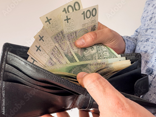  man takes Polish zlotys from his wallet. Man counting money pln