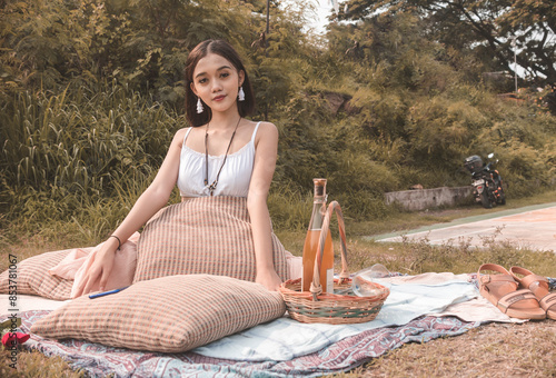 Young woman enjoying picnic with boho fashion style outdoors photo