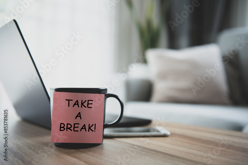 Take a break is written on a post-it and stuck on a coffee mug on my desk. It's a reminder that it's time to take a break from work.