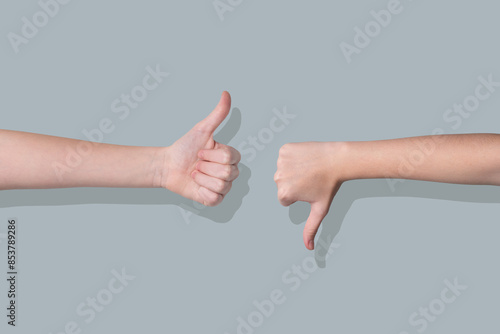 Photography Two hands showing thumbs up and thumbs down gestures on a gray background