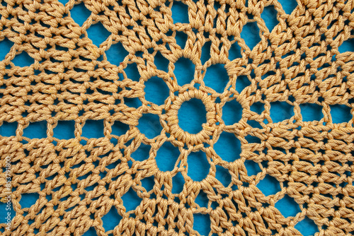 Beige doily crochet pattern on blue background, abstract close up texture