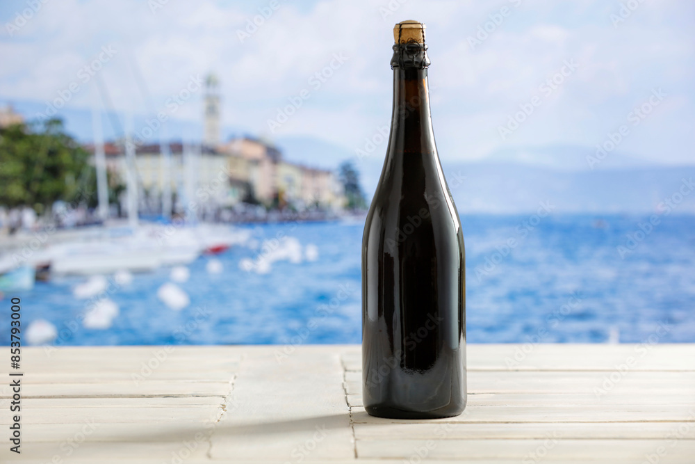 Bottle of wine and white desk with landscape of Garda Lake . Bottle of wine and white desk with landscape of Garda Lake .