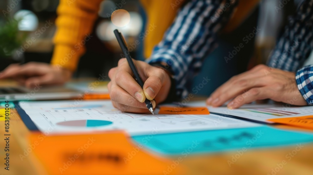 Close-up view of hands analyzing and pointing at financial business charts on a table Close-up view of hands analyzing and pointing at financial business charts on a table