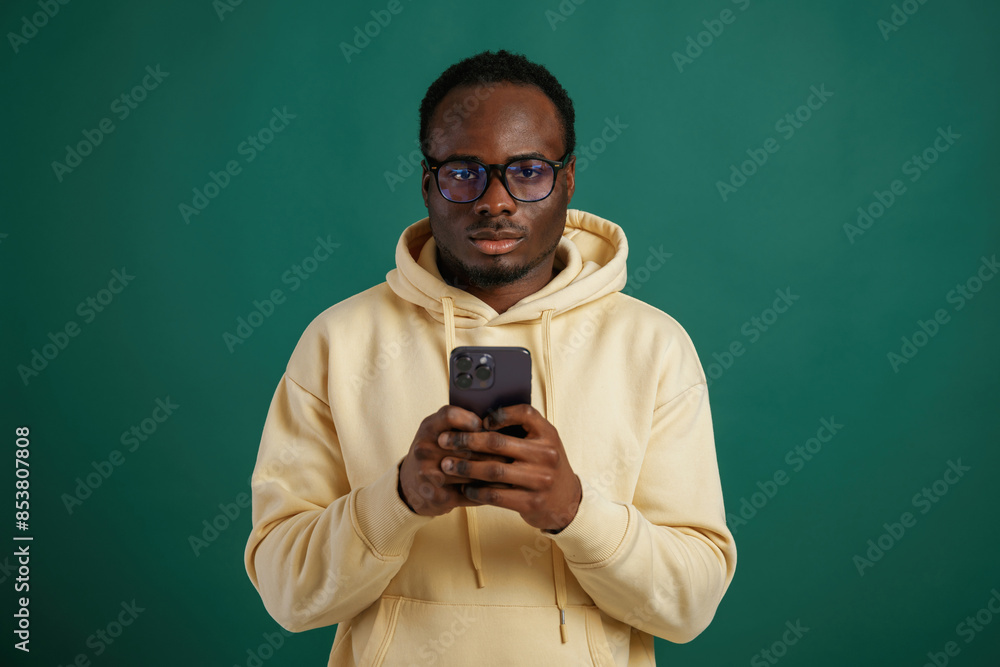 Using smartphone. African American man is standing against green background in the studio Using smartphone. African American man is standing against green background in the studio