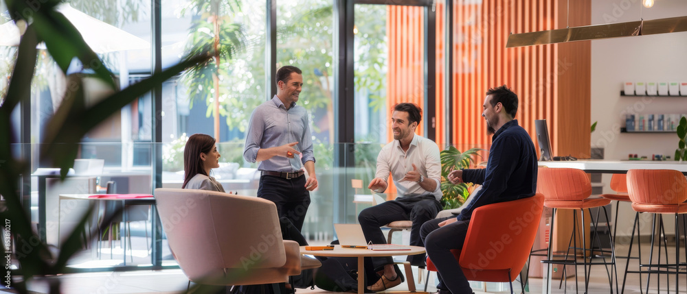 Obraz premium Colleagues having an engaging discussion in a bright, modern office space with large windows, comfortable furniture, and natural light.