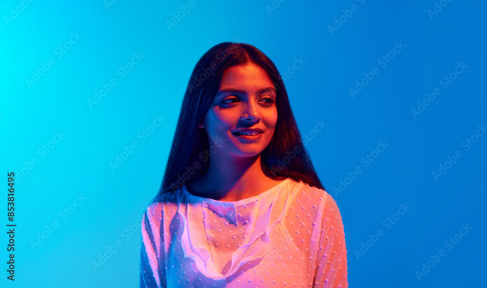 Young beautiful woman dressed white festive shirt posing looking away in neon light against blue gradient background. Concept of human emotions, fashion beauty, facial-expression. Ad Young beautiful woman dressed white festive shirt posing looking away in neon light against blue gradient background. Concept of human emotions, fashion beauty, facial-expression. Ad