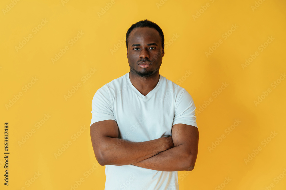 Black man is in the studio against yellow background Black man is in the studio against yellow background