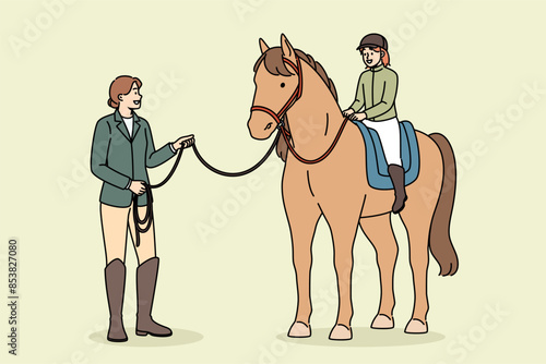 Little girl learns to ride horse and be jockey or rider, under supervision of female trainer. Riding lesson for happy child and building confidence or maintaining balance for future jockey