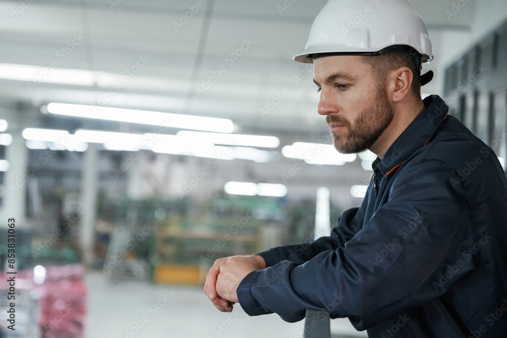 Leaning on the railings. Factory worker is indoors with hard hat Leaning on the railings. Factory worker is indoors with hard hat