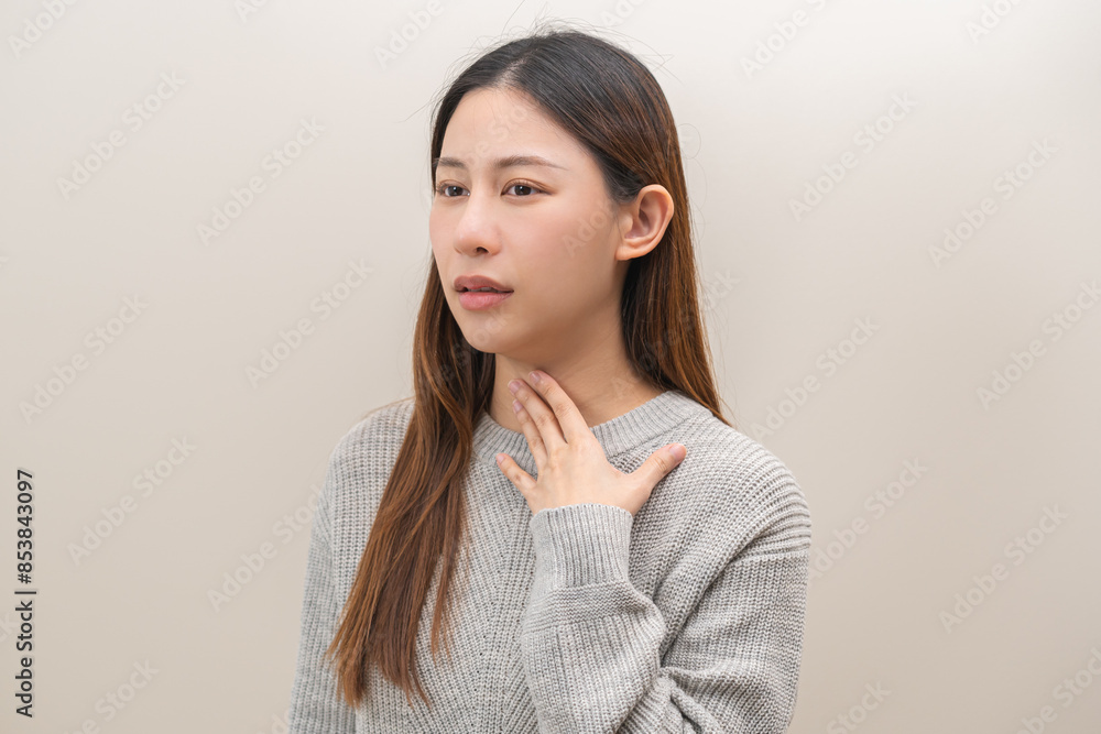 Sickness in inflaming asian young woman, girl use hand check self touch at sore throat, pain thyroid gland on neck or disease reflux, acid of suffer people on wall background. Medical and healthcare. Sickness in inflaming asian young woman, girl use hand check self touch at sore throat, pain thyroid gland on neck or disease reflux, acid of suffer people on wall background. Medical and healthcare.