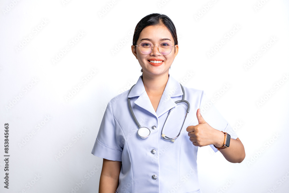 Portrait of smiling Asian female doctor with stethoscope on her shoulder and showing thumb up, isolated on gray background. Portrait of smiling Asian female doctor with stethoscope on her shoulder and showing thumb up, isolated on gray background.