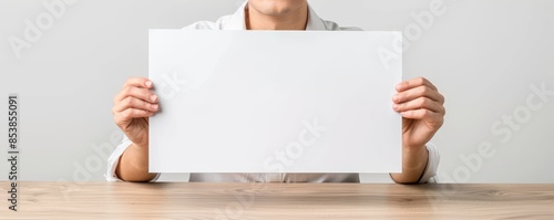 Person holding a blank white sheet of paper on a wooden table, ready for message, text, or artwork. Ideal for mockups and design templates. photo