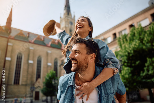 Playful couple of travelers having fun while piggybacking in  city. photo