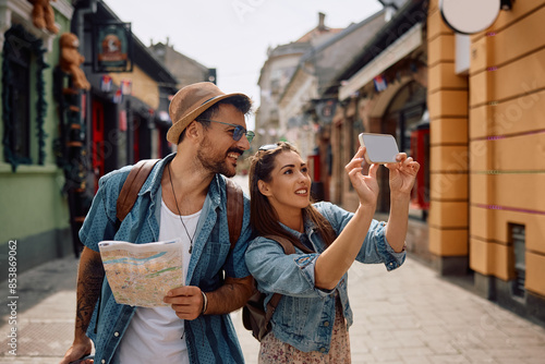 Bild auf Leinwand Happy tourist couple taking selfie while exploring  city.