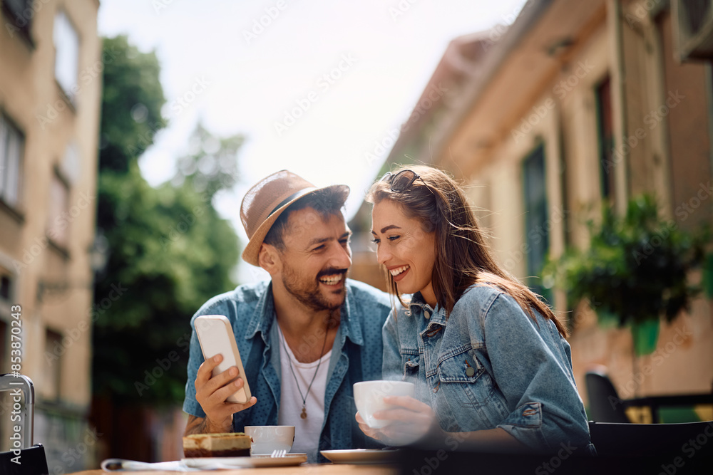 Happy couple using cell phone while drinking coffee in city. Happy couple using cell phone while drinking coffee in city.