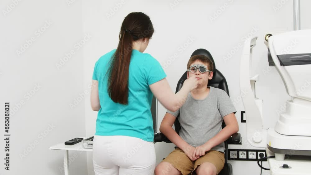 Happy little patient in an ophthalmology clinic. Eye test, cheerful child trying on trial frames during optometric examination for accuracy. Happy little patient in an ophthalmology clinic. Eye test, cheerful child trying on trial frames during optometric examination for accuracy.