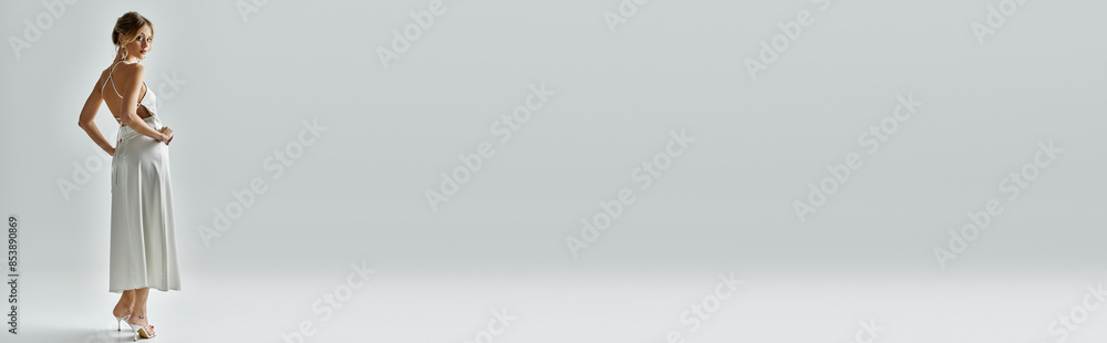 A young woman in a white dress exudes elegance in a bright white room. A young woman in a white dress exudes elegance in a bright white room.