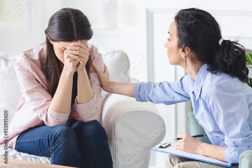 Crying woman is seated on a couch, engaged in conversation with a therapist. Both individuals seem attentive and focused on the discussion taking place.