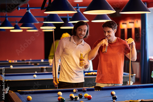 Friends play pool in a dimly lit room, enjoying drinks and each others company. photo