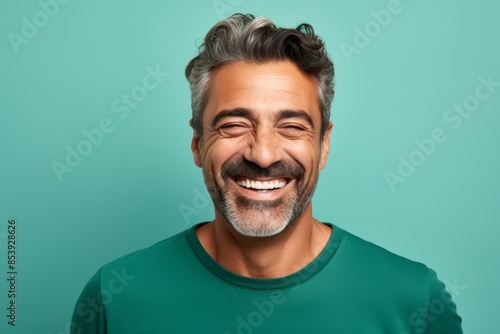 
Portrait photo of a happy Middle Eastern man, 45 years old, winking on a pastel teal background photo