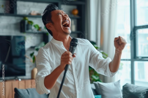 Portrait of a blissful asian man in his 40s dancing and singing song in microphone in modern minimalist interior © CogniLens