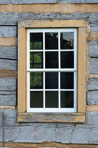 Looking at a window on an old pioneer log home from the outside.