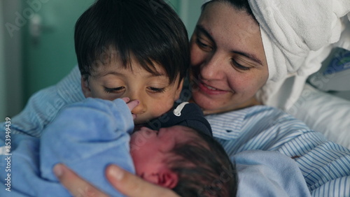 Family Welcoming Newborn at Hospital - Brother holding infant in arms as mother watches, Siblings Bonding for the First Time Post-Childbirth