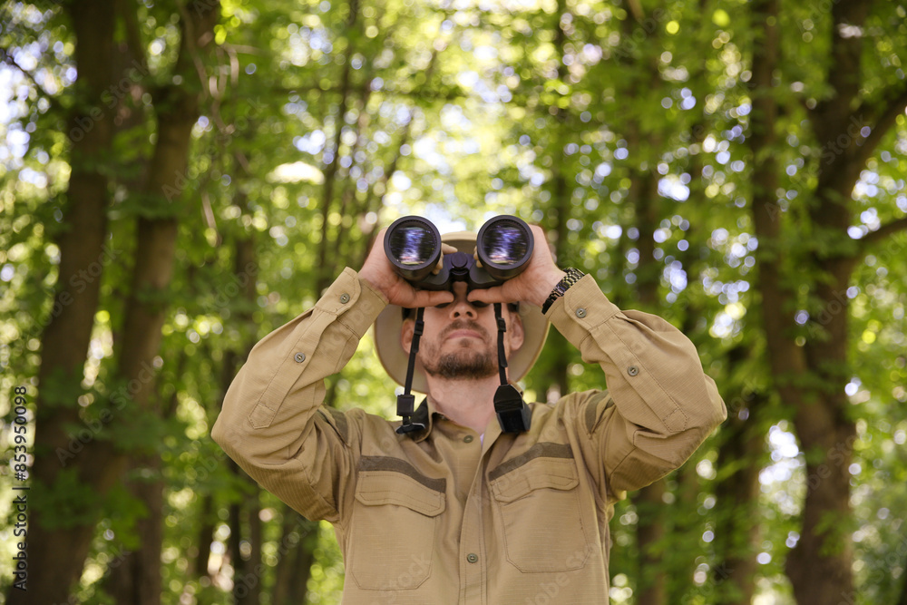 Forester with binoculars examining plants in forest Forester with binoculars examining plants in forest