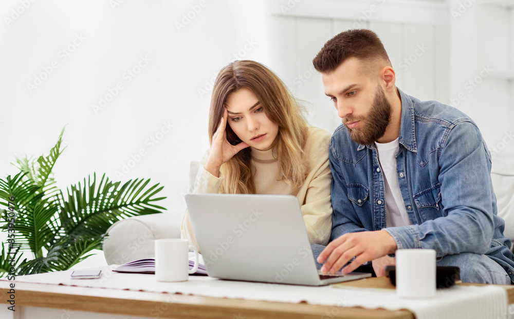 A man and a woman sitting together, focused on a laptop screen. A man and a woman sitting together, focused on a laptop screen.