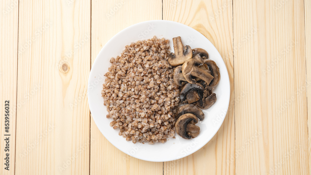 Buckwheat porridge with fried mushrooms on a plate on a wooden background. Healthy diet food. The concept of healthy eating Buckwheat porridge with fried mushrooms on a plate on a wooden background. Healthy diet food. The concept of healthy eating