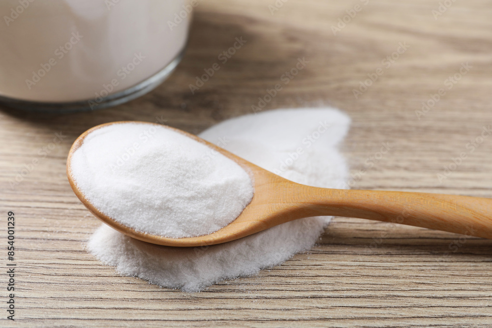 Baking soda in spoon on wooden table, closeup Baking soda in spoon on wooden table, closeup