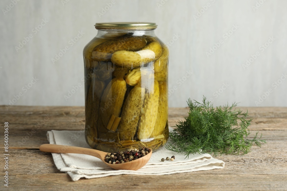 Pickled cucumbers in jar, dill and peppercorns on wooden table Pickled cucumbers in jar, dill and peppercorns on wooden table