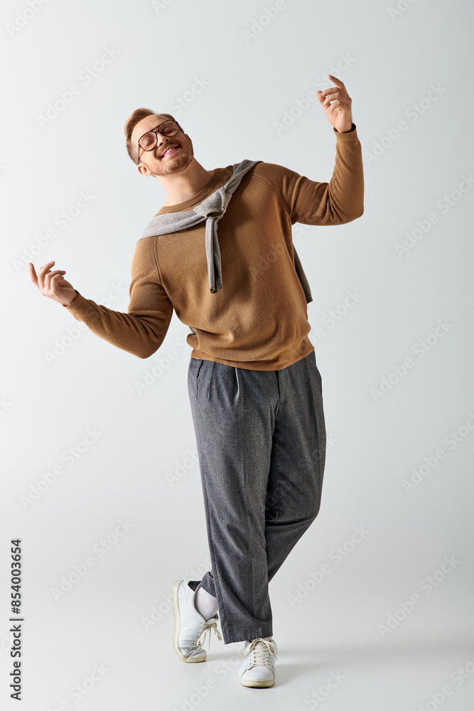 Handsome man in brown sweater and gray pants striking a pose. Handsome man in brown sweater and gray pants striking a pose.